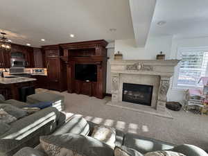 Living room with sink, an inviting chandelier, light carpet, a textured ceiling, and a premium fireplace