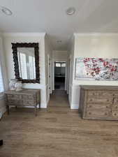 Corridor with wood-type flooring, plenty of natural light, and crown molding