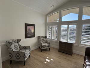 Sitting room with a wealth of natural light, vaulted ceiling, and light hardwood / wood-style floors