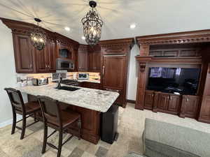 Kitchen with hanging light fixtures, paneled fridge, sink, and kitchen peninsula