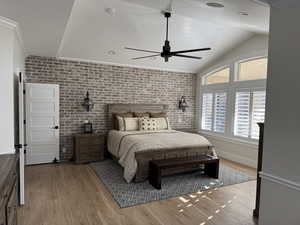 Bedroom with wood-type flooring, brick wall, ornamental molding, and ceiling fan