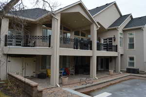 Rear view of house featuring central AC unit, a patio, and a balcony