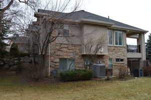 Rear view of house with a lawn, a balcony, and central air condition unit