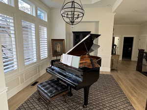 Misc room with an inviting chandelier, crown molding, and light hardwood / wood-style floors