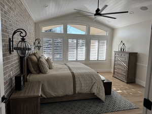 Bedroom featuring wood ceiling, vaulted ceiling, light wood-type flooring, ceiling fan, and brick wall