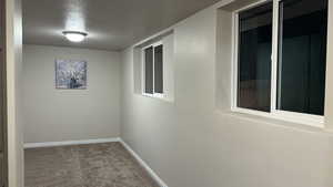 Hallway with a textured ceiling and carpet flooring