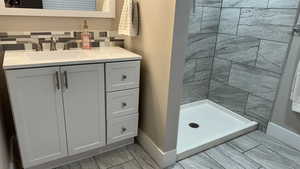 Bathroom featuring vanity, backsplash, and tiled shower