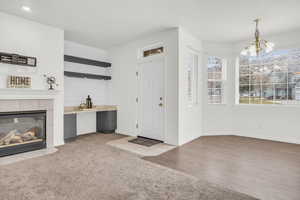 Carpeted entrance foyer featuring a fireplace and a chandelier