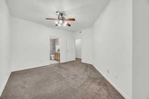 Unfurnished bedroom with ceiling fan, light colored carpet, and ensuite bath