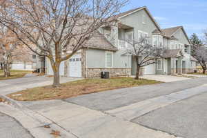 View of front of house featuring a garage, a balcony, and central AC unit