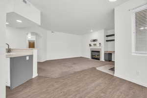 Unfurnished living room featuring sink, a tile fireplace, and light hardwood / wood-style flooring