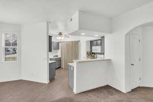 Kitchen with ceiling fan, wood-type flooring, gray cabinets, and kitchen peninsula