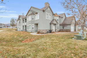 View of side of property with central AC unit and a lawn