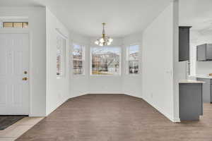 Unfurnished dining area featuring a textured ceiling, a chandelier, and light hardwood / wood-style flooring