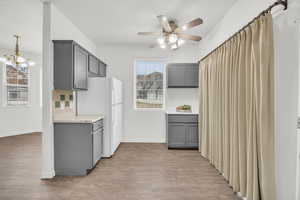 Kitchen with pendant lighting, gray cabinets, light hardwood / wood-style floors, and white fridge