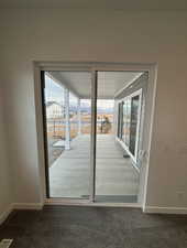 Doorway to outside with dark colored carpet