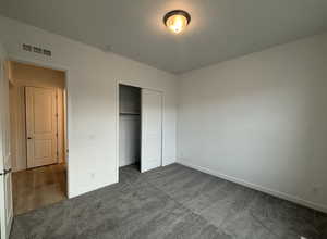 Unfurnished bedroom featuring dark carpet and a closet