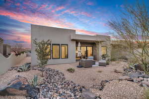 Back house at dusk with outdoor lounge area and a patio area