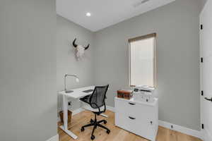 Office with light wood-style floors and recessed lighting