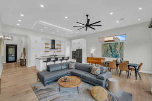 Living room with sink, ceiling fan with notable chandelier, and light hardwood / wood-style flooring