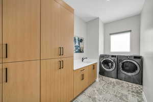 Laundry area with washing machine and dryer, cabinet space, light tile patterned floors, and baseboards