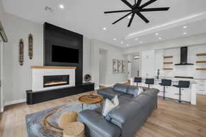 Living room with ceiling fan, light wood-type flooring, sink, and a fireplace