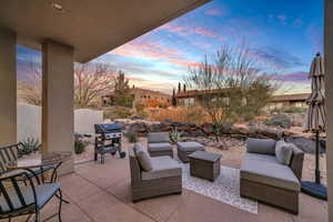 Patio terrace at dusk featuring outdoor lounge area and a grill