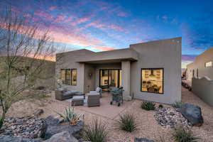 Back house at dusk with an outdoor living space and a patio area