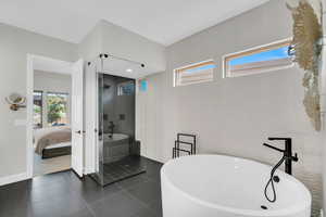 Full bathroom with a shower stall, ensuite bathroom, a soaking tub, tile patterned floors, and baseboards