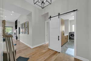 Corridor featuring washer / clothes dryer, light hardwood / wood-style flooring, and a barn door