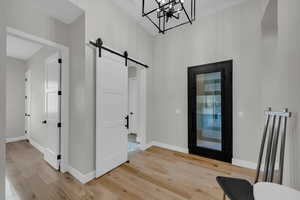 Entryway with a barn door, a chandelier, and light hardwood / wood-style flooring