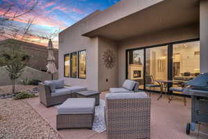 Patio terrace at dusk with an outdoor living space with a fireplace