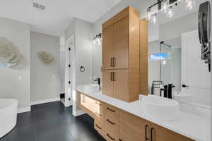 Bathroom with tile patterned floors, vanity, and a bath