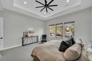 Bedroom featuring ceiling fan, a raised ceiling, and carpet floors