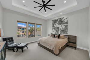 Carpeted bedroom featuring a tray ceiling