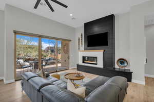 Living room featuring ceiling fan, a fireplace, and light hardwood / wood-style flooring