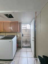 Clothes washing area with cabinets, washer and dryer, light tile, back door separate  entrance