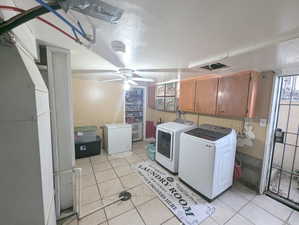 Clothes washing area with cabinets, light tile patterned floors, washer and dryer, and ceiling fan