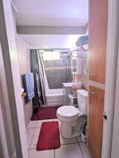 Bathroom with tile patterned flooring, shower / bath combination with curtain, and toilet