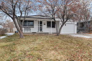 Single story home featuring a porch, a garage, and a front yard