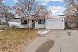 Ranch-style home with a garage, covered porch, and a front lawn