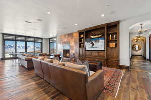 Living room with dark wood-type flooring, a mountain view, a notable chandelier, a wall of windows, and a fireplace