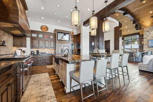 Kitchen with decorative light fixtures, sink, range with two ovens, a large island, and custom range hood