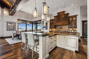 Kitchen with dark brown cabinetry, sink, dark hardwood / wood-style floors, beamed ceiling, and decorative backsplash