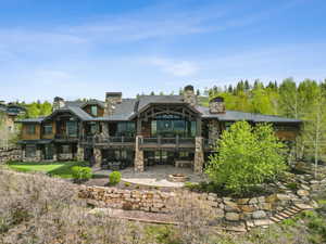 Rear view of house with a standing seam roof, stone siding, an outdoor fire pit, a patio area, and metal roof