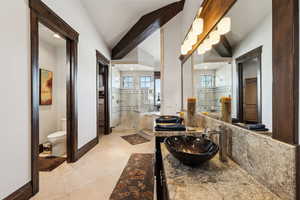 Bathroom with tile patterned floors, toilet, lofted ceiling with beams, and vanity