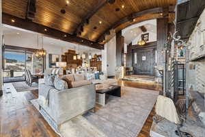 Living room featuring high vaulted ceiling, wooden ceiling, dark hardwood / wood-style flooring, a notable chandelier, and beam ceiling