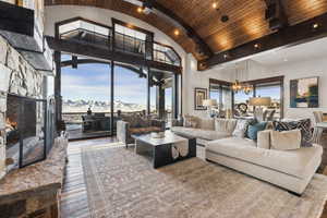 Living room featuring hardwood / wood-style flooring, a healthy amount of sunlight, a stone fireplace, and a mountain view