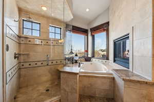 Bathroom featuring lofted ceiling, plenty of natural light, plus walk in shower, and a tile fireplace