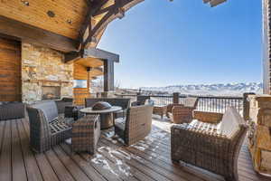 Snow covered deck featuring a mountain view and an outdoor living space with a fireplace